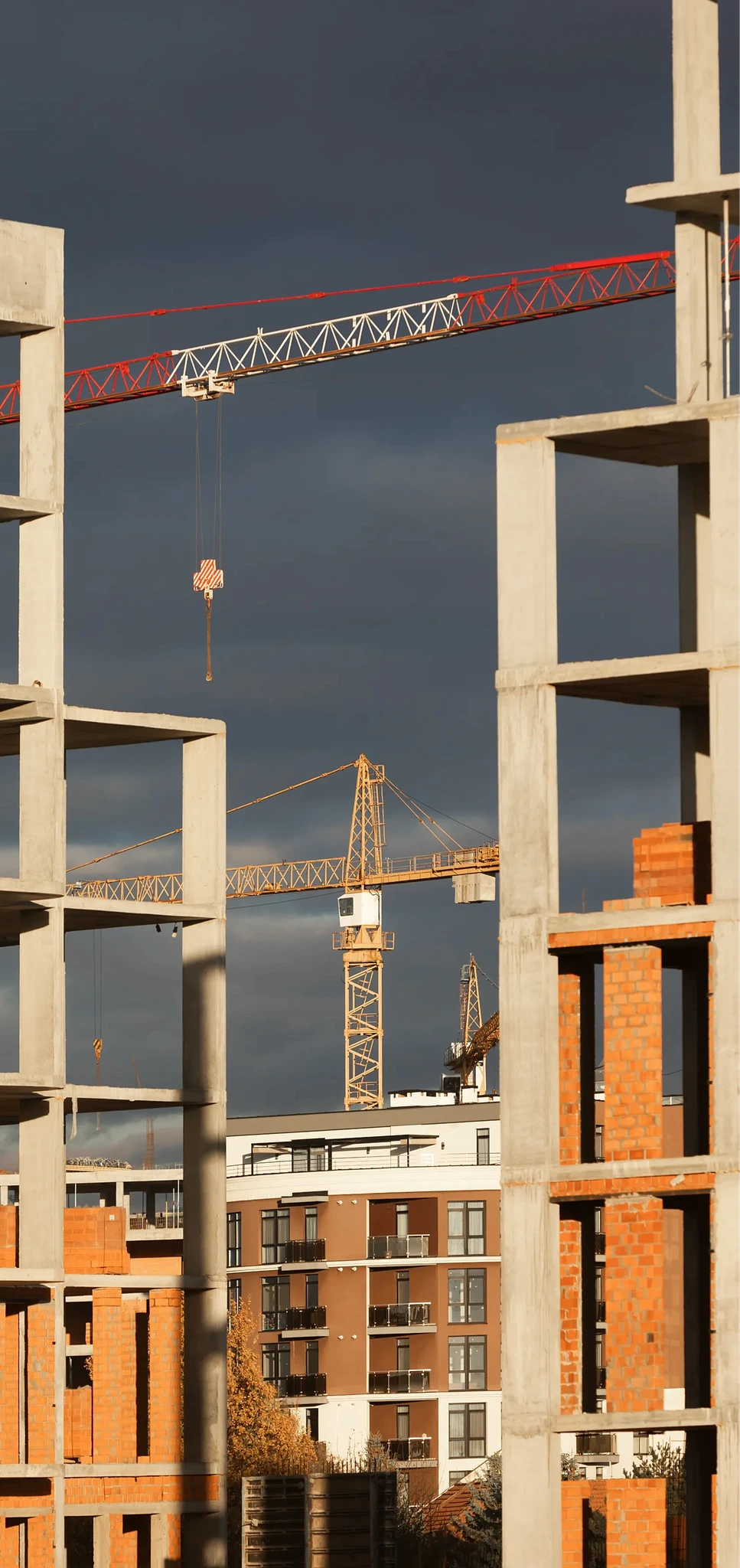 Construction crane silhouetted against a dusk sky on an active build site.